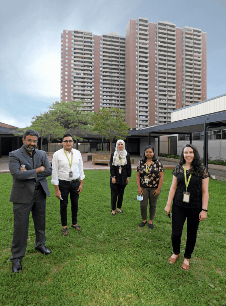 Group of five WoodGreen staff members standing socially distanced outside a building.