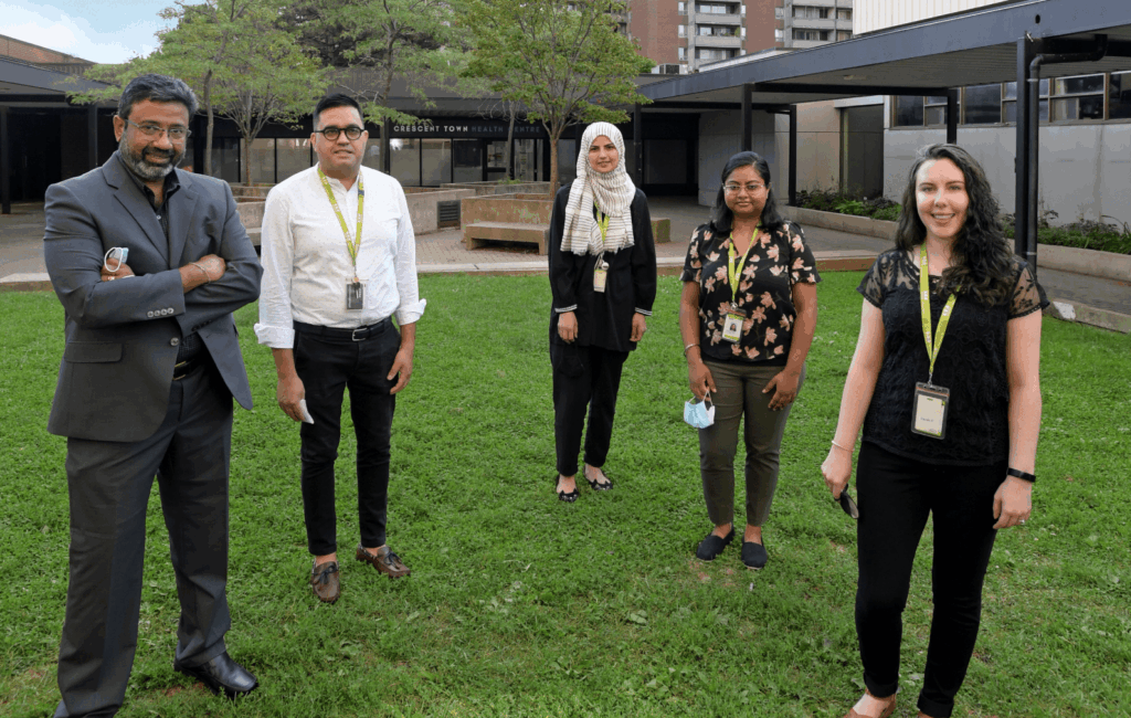 Group of five WoodGreen staff members standing socially distanced outside a building.
