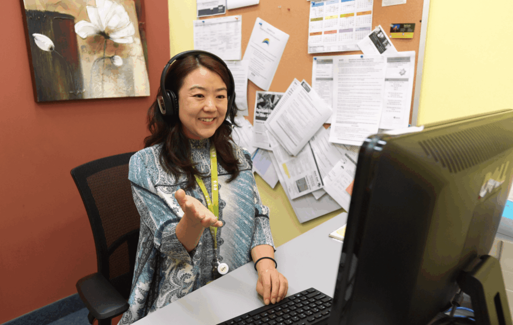 A WoodGreen worker answering a call at her desk in front of her computer