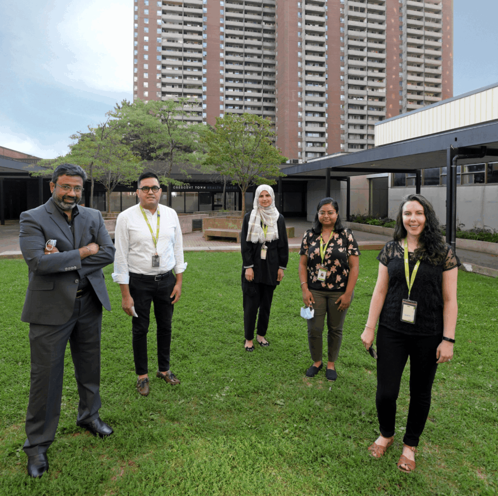 Group of five WoodGreen staff members standing socially distanced outside a building.