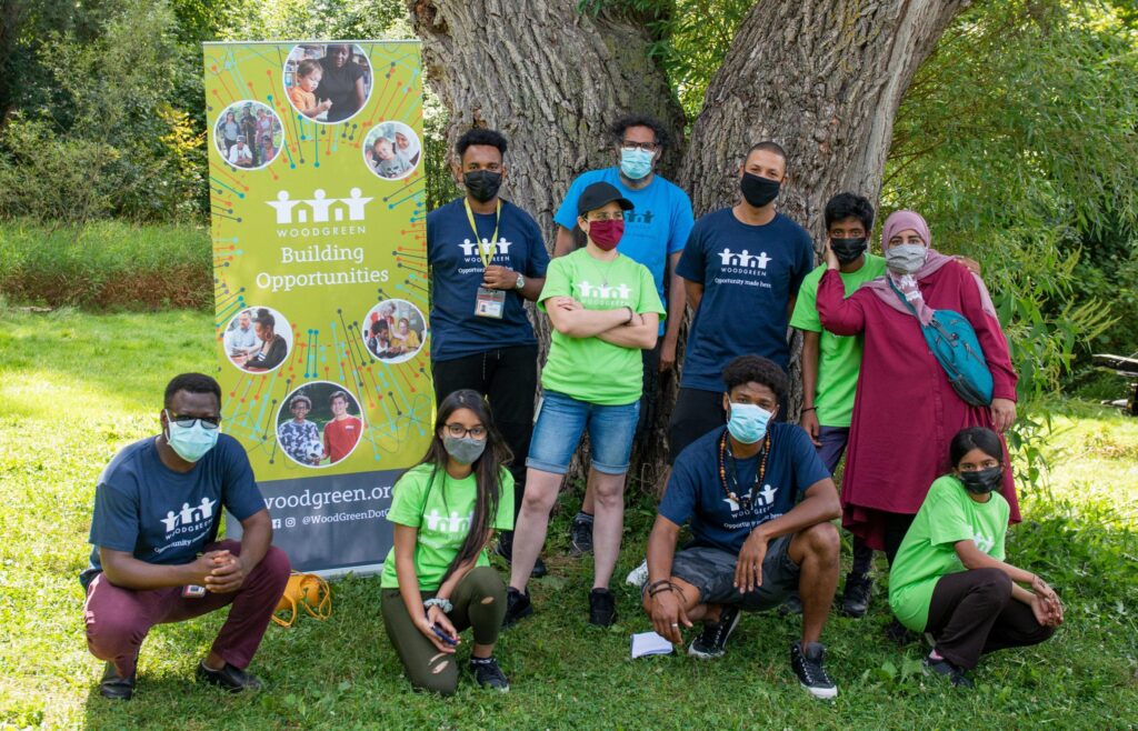 A group of 10 people standing outside in front of a tree, all wearing masks and in different poses.