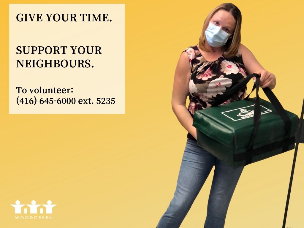 A woman in jeans wearing a mask carries a hot meal delivery bag