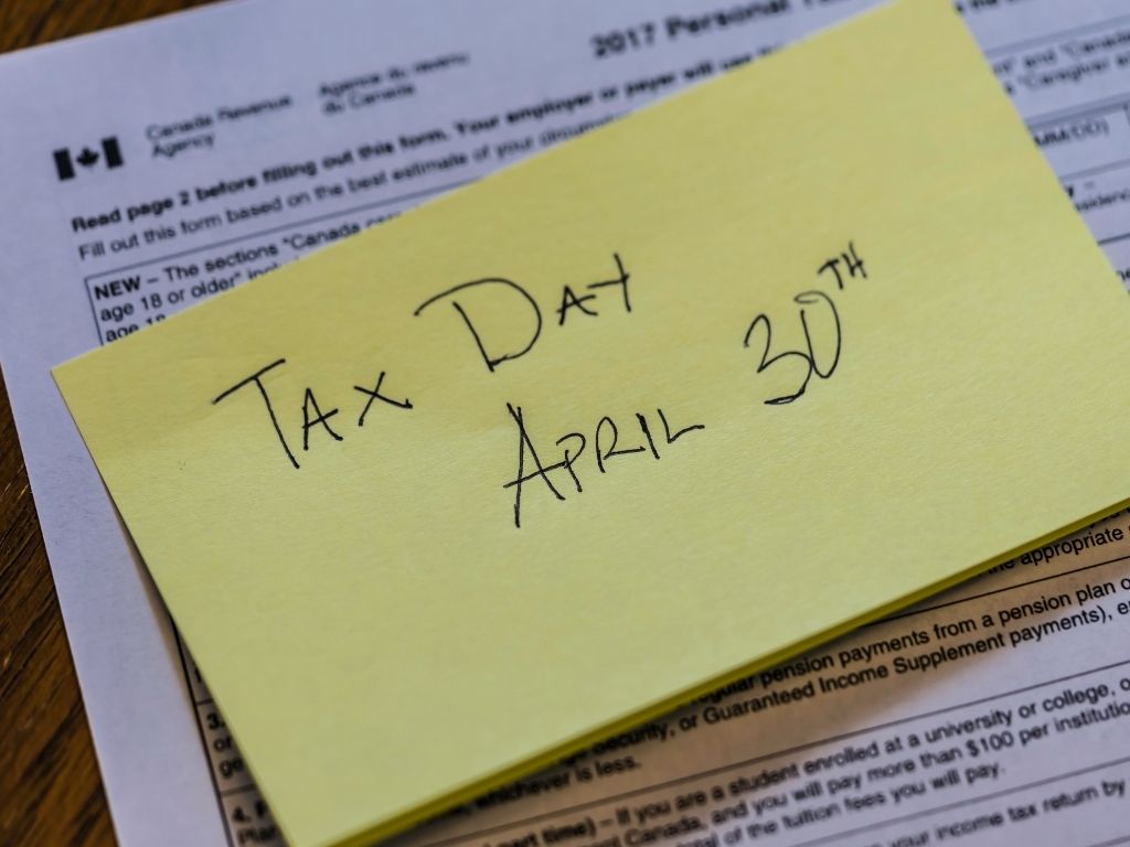 canadian income tax documents with sticky note listing April 30th as final tax day in Canada
