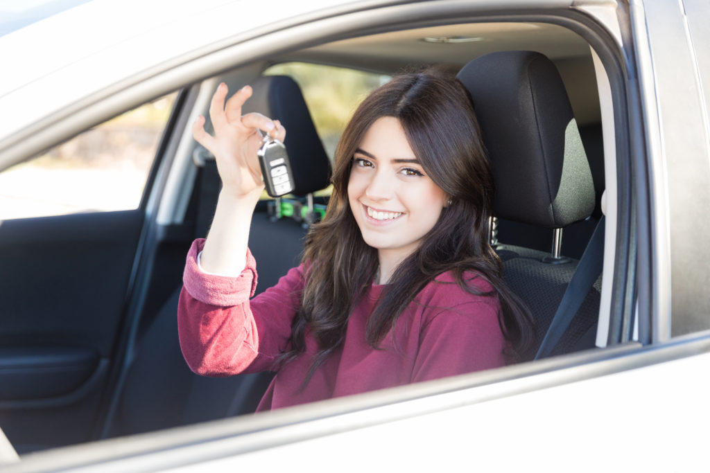 Portrait of gorgeous woman smiling while showing key in car