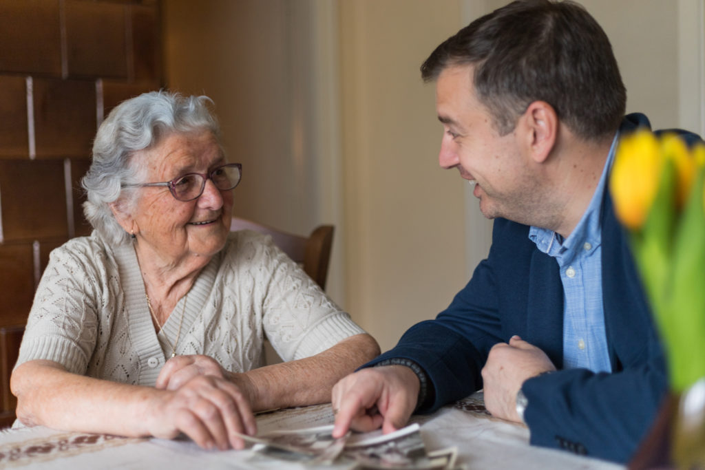 Senior woman with her adult grandson are looking old photos and remember the old memories.Man enjoys the company of his grandmother and spending wonderful time with her.<br />