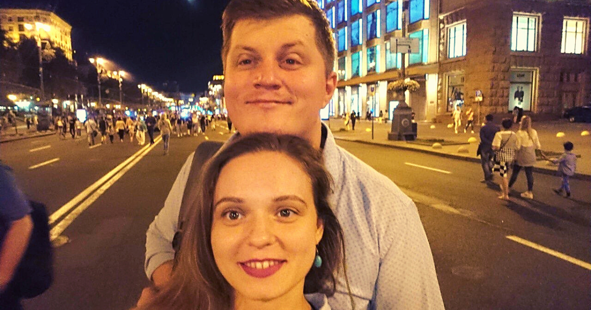 a man and woman stand on a busy shopping street at night in Georgia