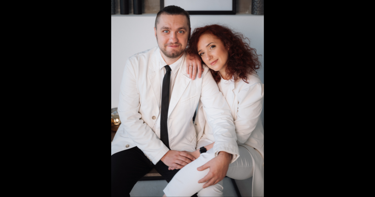 A man and woman, both wearing white, pose while sitting in Ukraine. 