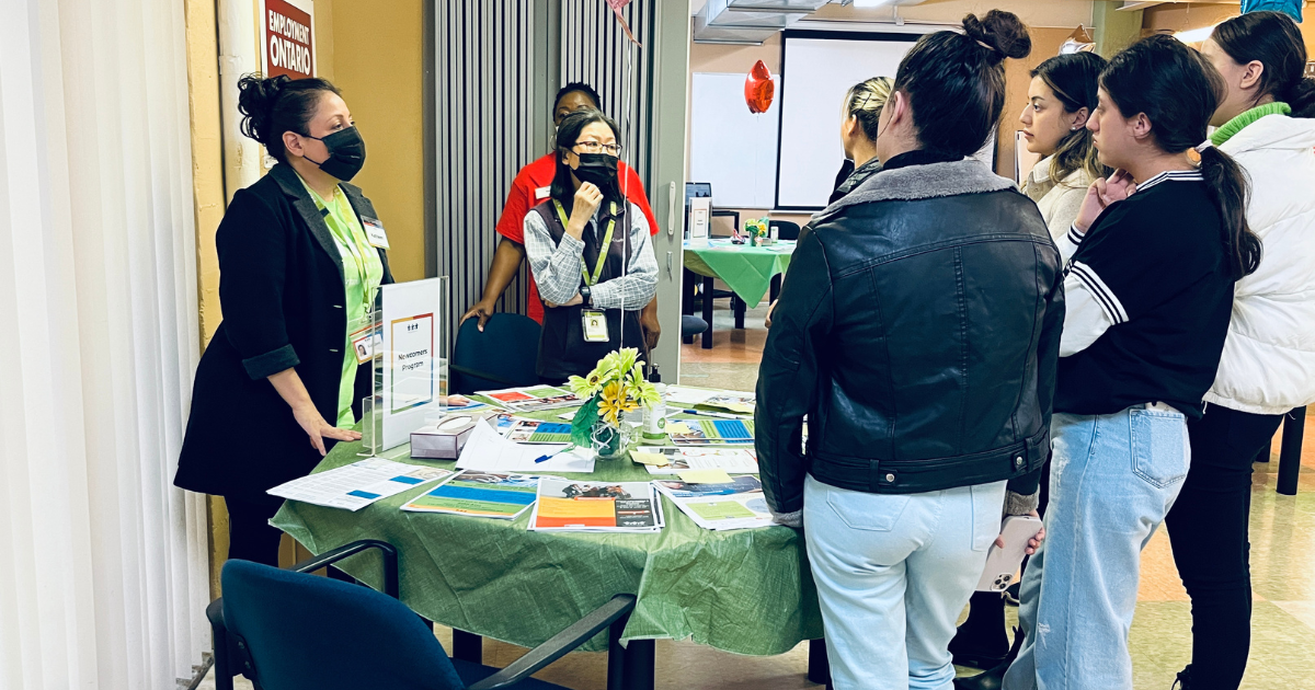 a group of people gather around a table full of brochures at a job search site