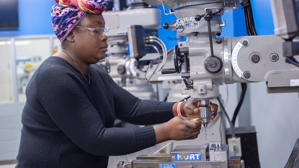 Black woman using CNC Machine as part of WoodGreen's CNC/Precision Machining Program