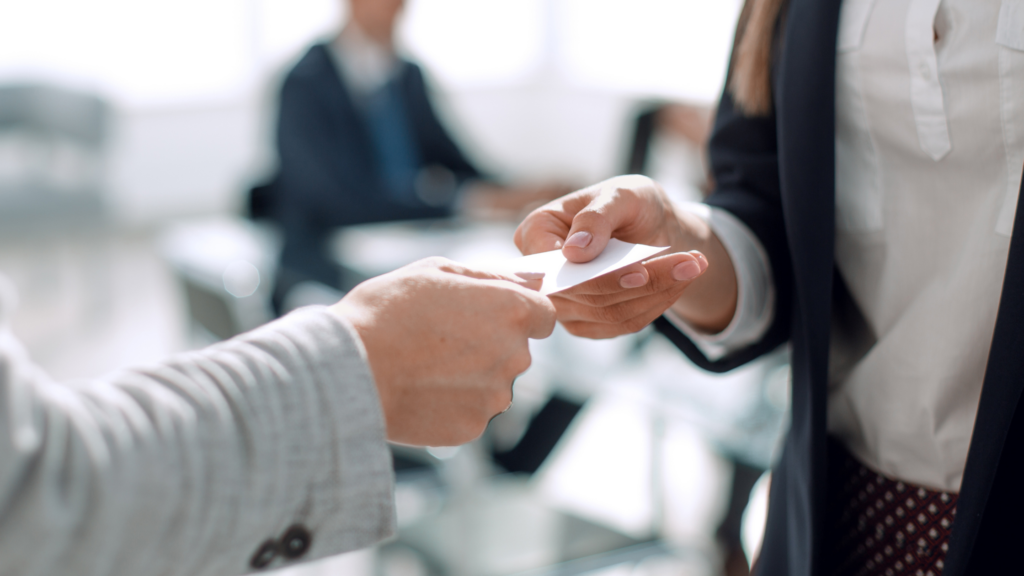 Someone hands another person a business card.