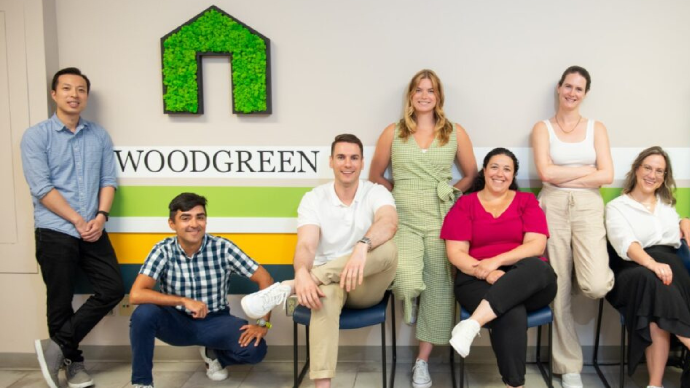 A photo of diverse staff in front of a wall that says "WoodGreen"