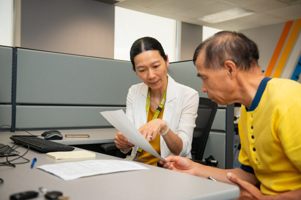 Staff helping client explain a document in the office.