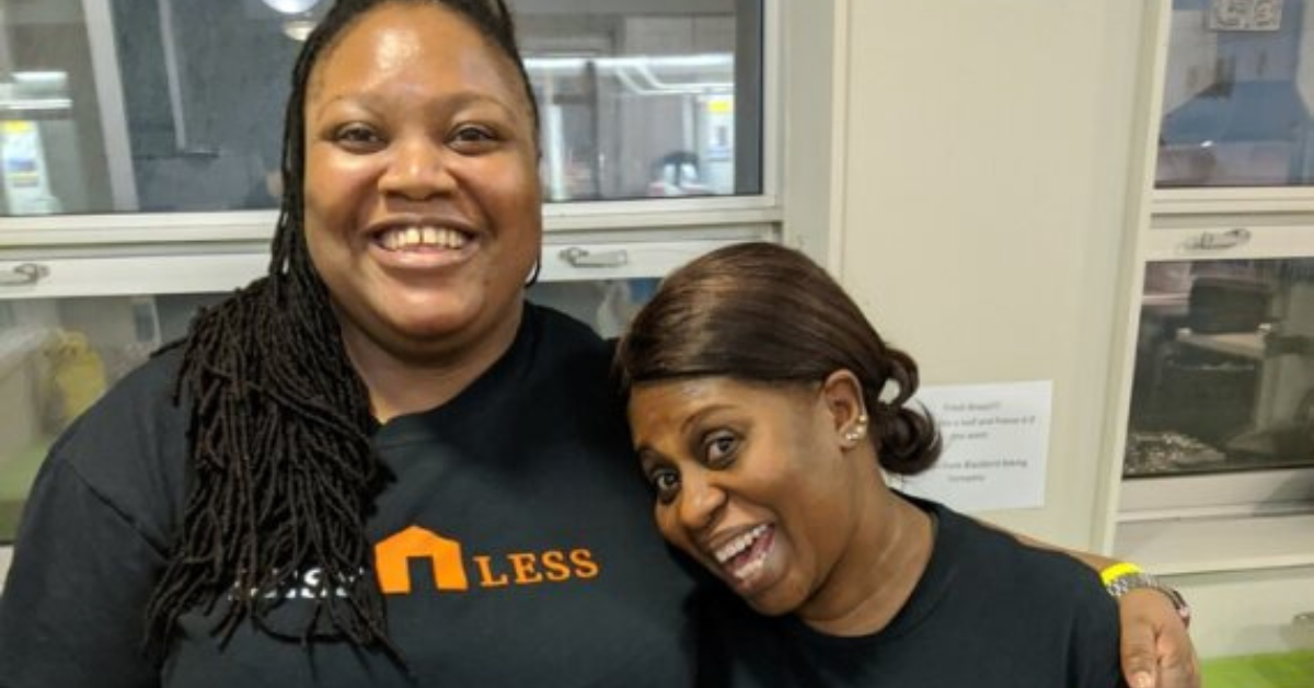 two women wearing dark tshirts smile playfully 